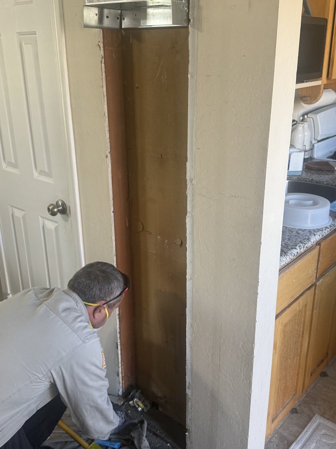 Technician prepping the empty wall cavity and vent connector before setting the new furnace, Newark