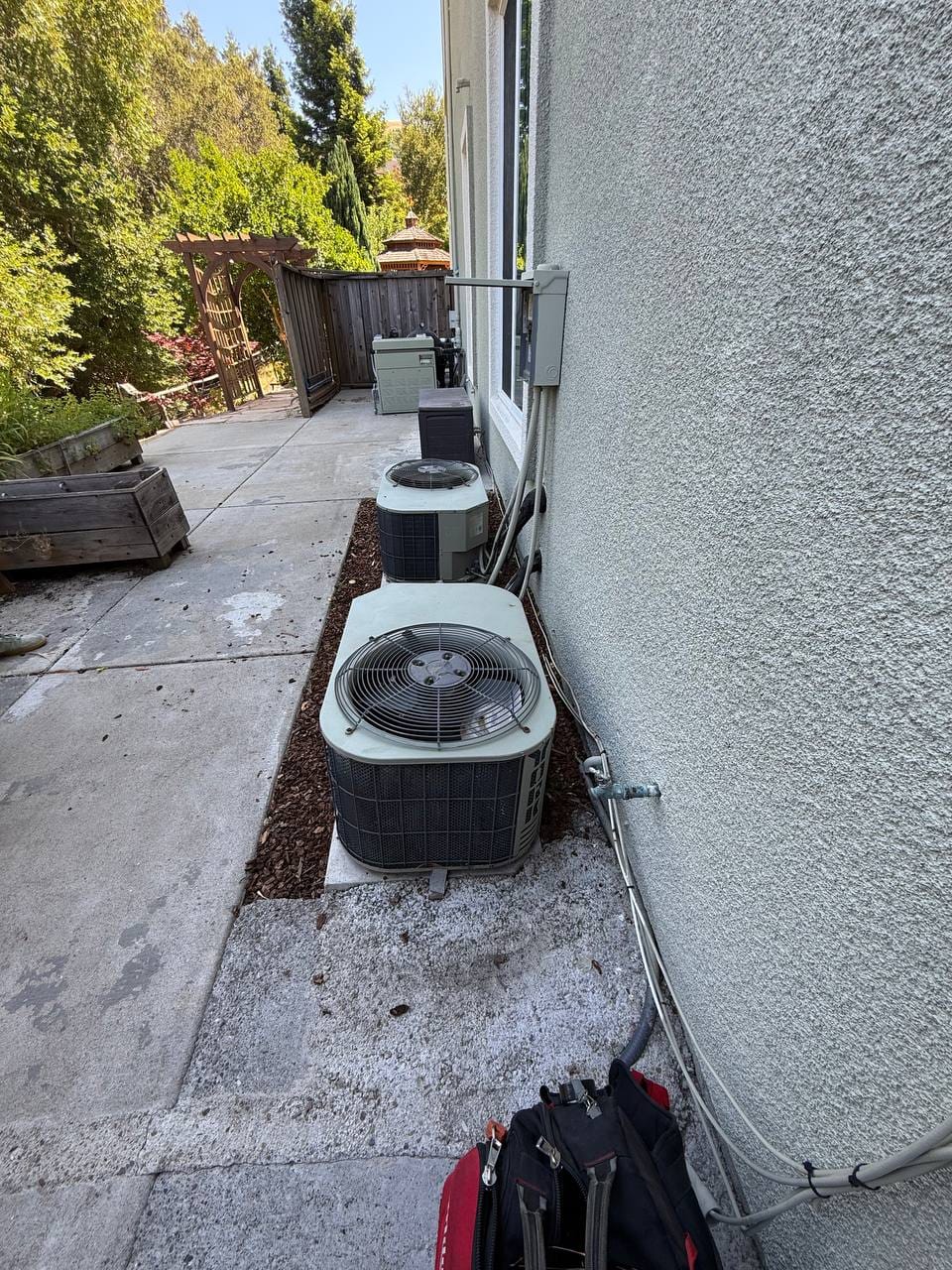 Two old R-22 AC condensers in place before removal during Carrier heat pump replacement, San Ramon