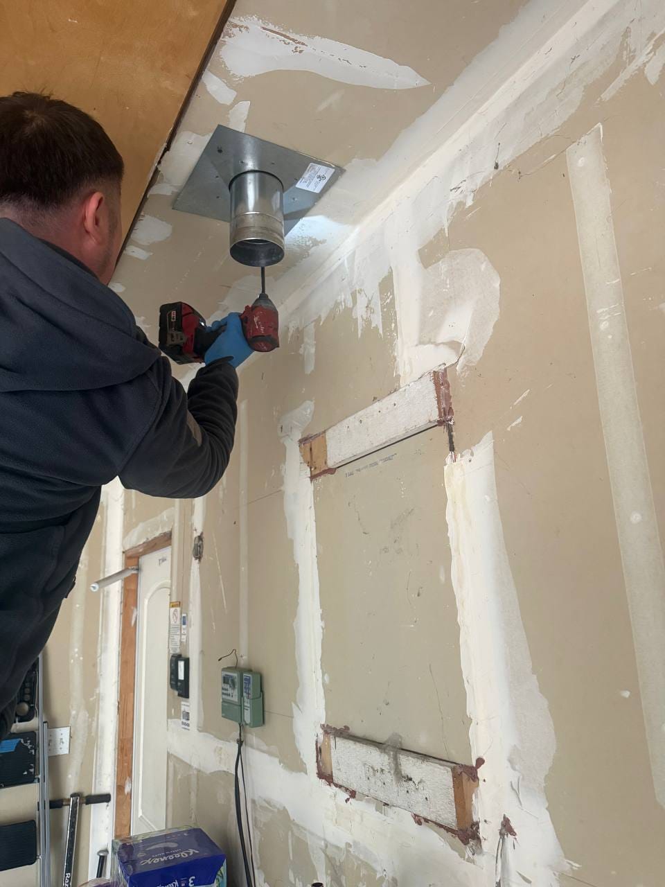 Technician fastening the new ceiling vent penetration box during Navien tankless install, Walnut Creek