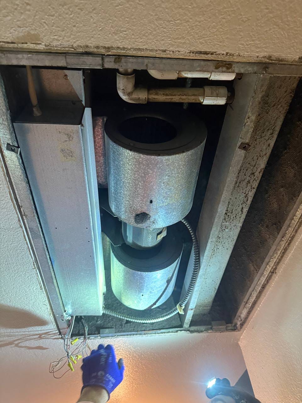 Technician working on the air handler blower in the ceiling cavity, San Ramon