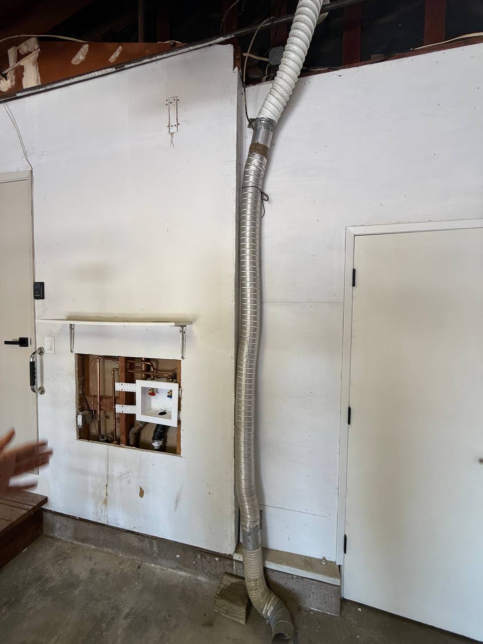 Flexible vent duct run and exposed plumbing wall cavity during installation, Martinez