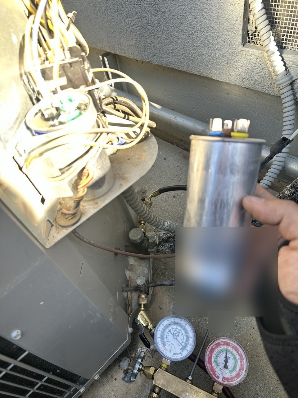 Capacitor held beside the open outdoor unit during the Los Gatos repair