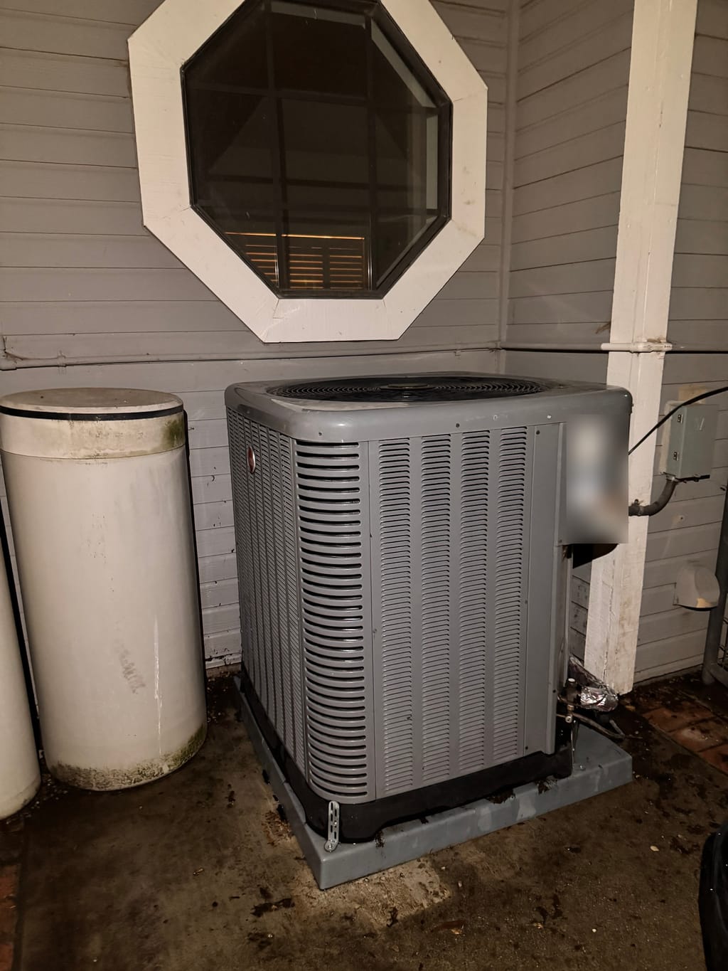Rheem outdoor unit reassembled below the same octagonal window after cleaning in Clayton