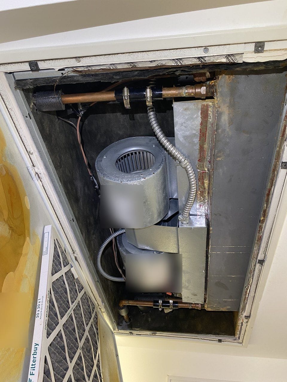 Ceiling-mounted AC air handler in Walnut Creek, CA, with the hinged filter panel swung down and yellow-brown stains on its inside